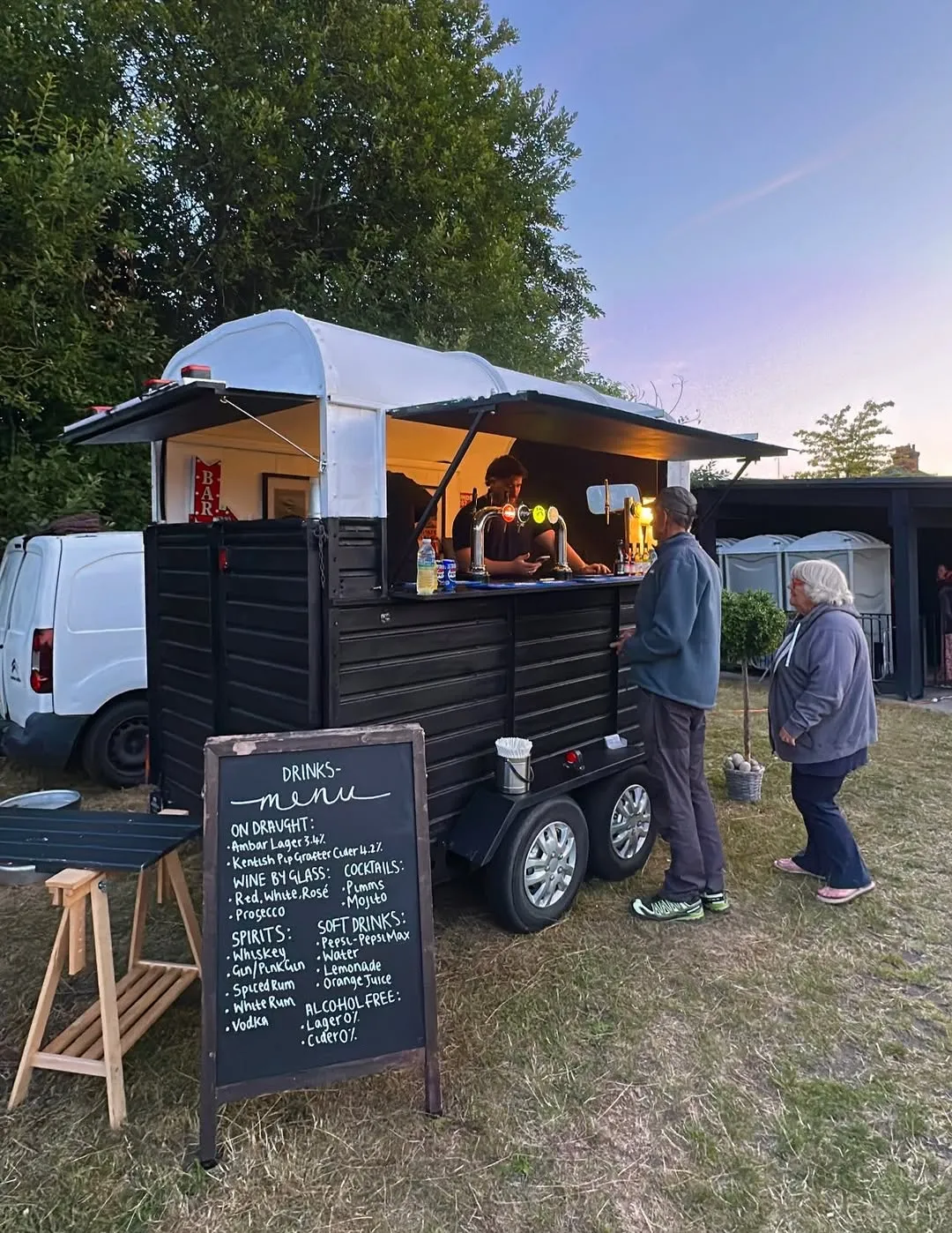 The little bars horsebox serving guests at a community event at dusk
